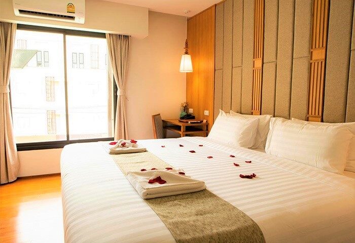 Lanna Thaphae Hotel room. Gay-friendly hotel bedroom with large bed, rose petals, and towels folded into hearts. Chiang Mai, Thailand.