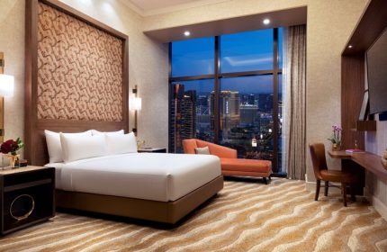 Las Vegas Hilton at Resorts World hotel room. Gay-friendly hotel with skyline view. Modern design, king bed, chaise lounge. Luxury travel.