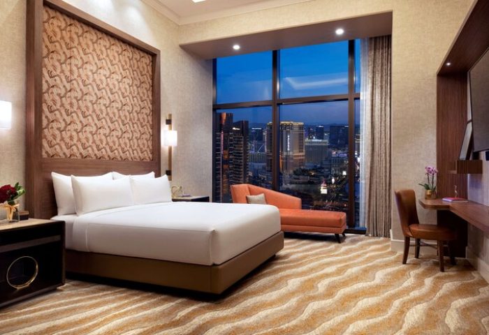 Las Vegas Hilton at Resorts World hotel room. Gay-friendly hotel with skyline view. Modern design, king bed, chaise lounge. Luxury travel.
