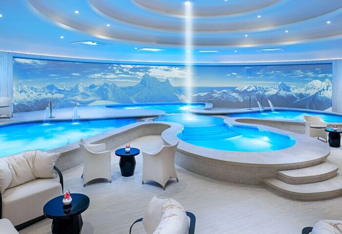 Las Vegas Hilton at Resorts World gay-friendly hotel spa. Indoor pools, mountain mural, lounge chairs, and blue lighting create a relaxing atmosphere.