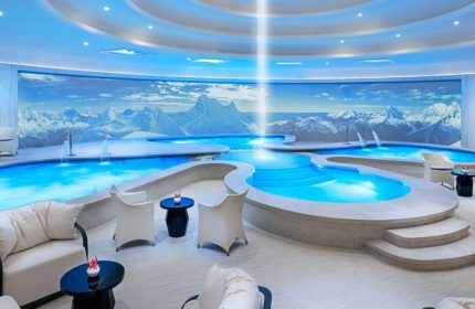 Las Vegas Hilton at Resorts World gay-friendly hotel spa. Indoor pools, mountain mural, lounge chairs, and blue lighting create a relaxing atmosphere.