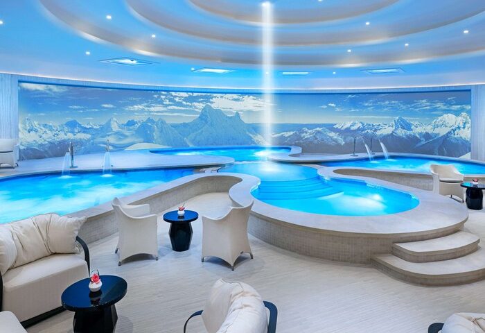 Las Vegas Hilton at Resorts World gay-friendly hotel spa. Indoor pools, mountain mural, lounge chairs, and blue lighting create a relaxing atmosphere.