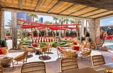 Las Vegas Hilton at Resorts World outdoor lounge area. Gay-friendly hotel with pool, seating, and palm trees. Perfect for gay travel in Las Vegas.