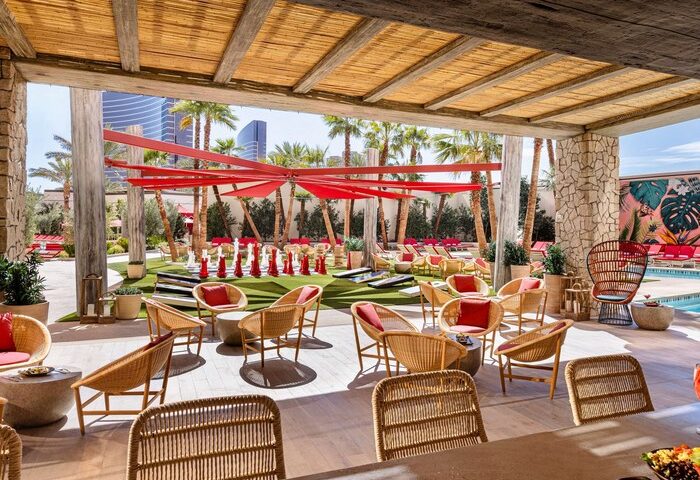 Las Vegas Hilton at Resorts World outdoor lounge area. Gay-friendly hotel with pool, seating, and palm trees. Perfect for gay travel in Las Vegas.