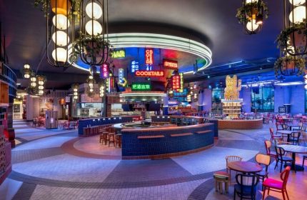 Interior of Gay-Friendly Las Vegas Hilton at Resorts World. Neon signs, bars, tables, and seating create a vibrant, welcoming atmosphere.