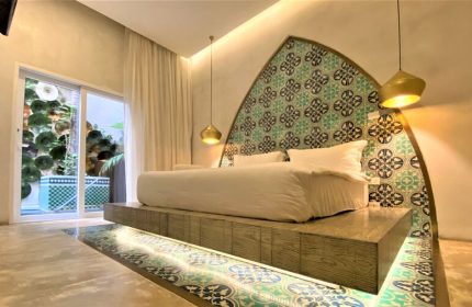 Layla Tulum Adults Only gay-friendly hotel room. Platform bed with decorative headboard and floor tiles. Luxury travel for gay men in Tulum.