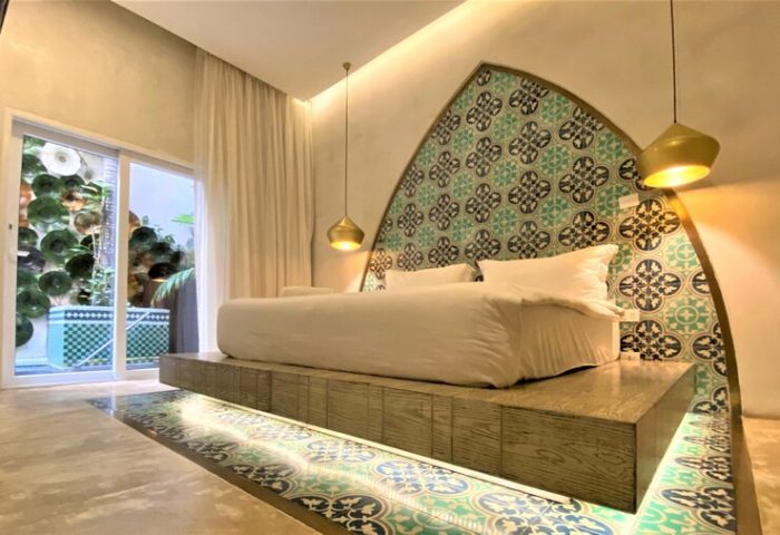Layla Tulum Adults Only gay-friendly hotel room. Platform bed with decorative headboard and floor tiles. Luxury travel for gay men in Tulum.