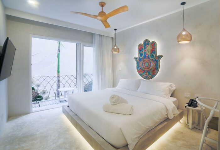 Layla Tulum Adults Only gay-friendly hotel room. White linens, Hamsa art, balcony, ceiling fan, and pendant lights. Modern design.