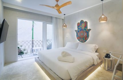 Layla Tulum Adults Only gay-friendly hotel room. White linens, Hamsa art, balcony, ceiling fan, and pendant lights. Modern design.