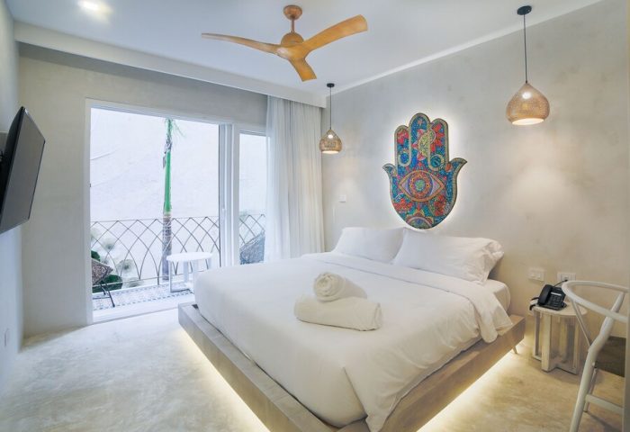 Layla Tulum Adults Only gay-friendly hotel room. White linens, Hamsa art, balcony, ceiling fan, and pendant lights. Modern design.