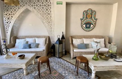 Layla Tulum Adults Only gay-friendly hotel lounge area. Wicker sofas, patterned tile floor, coffee tables, and Hamsa art create a chill vibe.