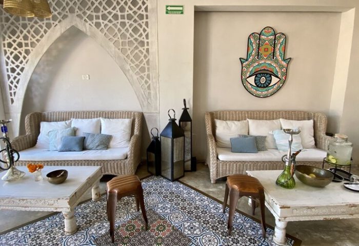 Layla Tulum Adults Only gay-friendly hotel lounge area. Wicker sofas, patterned tile floor, coffee tables, and Hamsa art create a chill vibe.