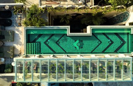 Layla Tulum Adults Only gay-friendly hotel aerial view. Green tiled pool, lounge area, and glass-enclosed space. Tulum travel.
