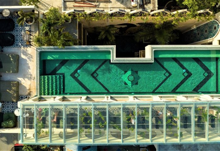 Layla Tulum Adults Only gay-friendly hotel aerial view. Green tiled pool, lounge area, and glass-enclosed space. Tulum travel.