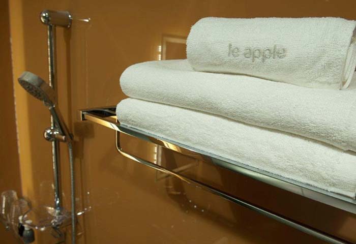 Bathroom at Le Apple Boutique Hotel Bukit Bintang, a gay-friendly hotel. Stacked white towels on a chrome rack, shower head visible.