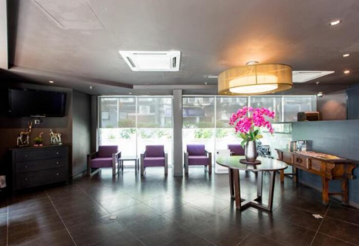 Le Apple Boutique Hotel Bukit Bintang lobby with purple chairs, floral arrangement, and dark furniture. Gay-friendly hotel interior.