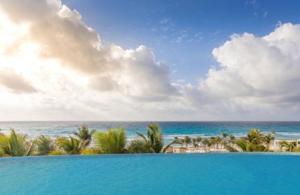 Infinity pool view at Le Blanc Resort Cancun Adults Only. All-inclusive, gay-friendly hotel with ocean backdrop and palm trees.