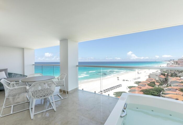 Le Blanc Resort Cancun adults-only all-inclusive gay-friendly hotel balcony view. Oceanfront, white furniture, and jacuzzi for a luxury vacation.