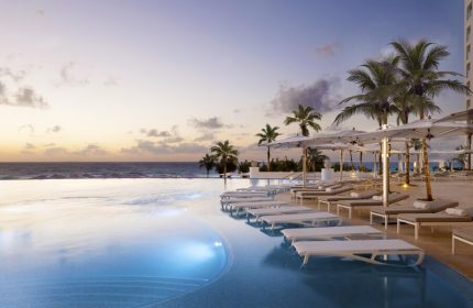 Le Blanc Resort Cancun adults-only all-inclusive gay-friendly hotel. Infinity pool, beach, palm trees, lounge chairs at sunset.
