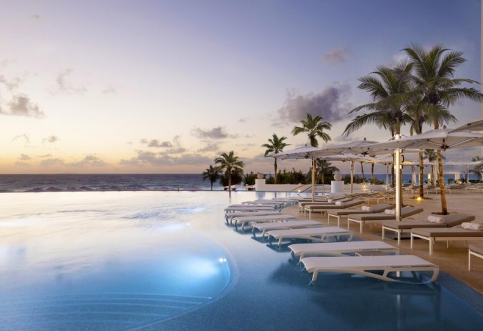Le Blanc Resort Cancun adults-only all-inclusive gay-friendly hotel. Infinity pool, beach, palm trees, lounge chairs at sunset.