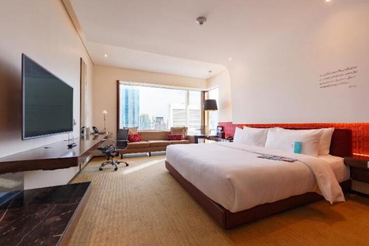 Le Méridien Bangkok hotel room. Modern interior with king bed, desk, and city view. Gay-friendly hotel for LGBTQ+ travelers in Bangkok.