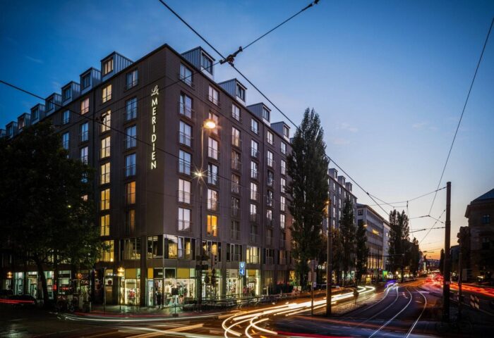 Le Méridien Munich hotel exterior at dusk. Gay-friendly hotel in Munich, Germany. Night shot with light trails from passing traffic.