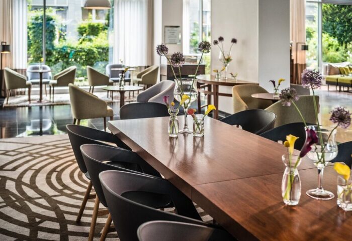 Le Méridien Munich's stylish interior. This gay-friendly hotel features modern decor, a large table with flowers, and comfortable seating areas.