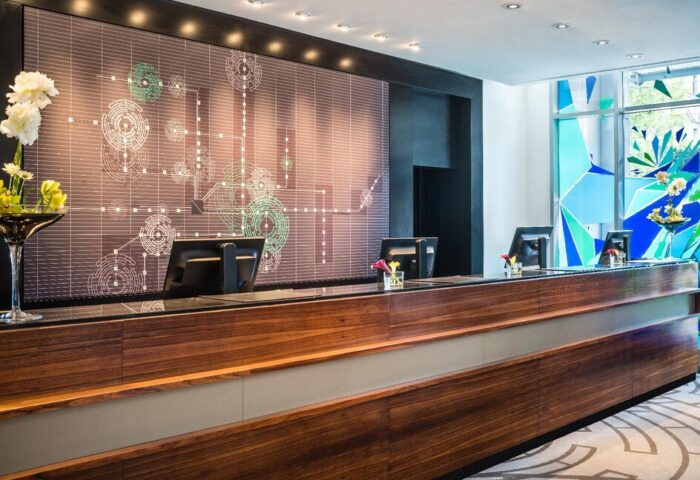 Le Méridien Munich's reception desk. Gay-friendly hotel with modern design, wood paneling, and geometric art. A welcoming space for travelers.