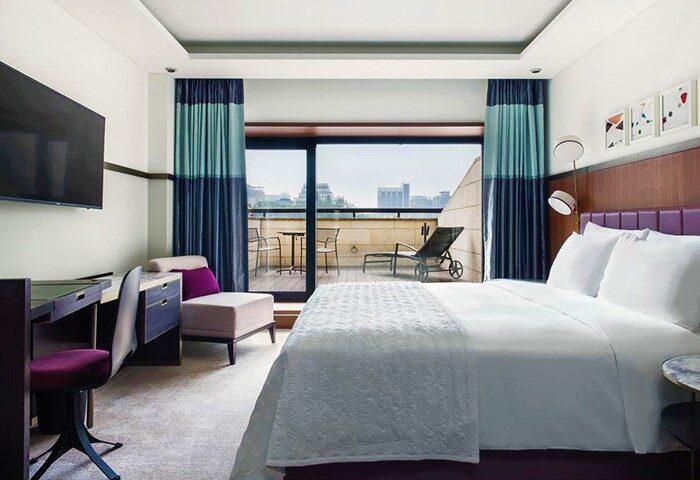 Le Meridien Seoul hotel room with balcony. Gay-friendly hotel featuring a bed, desk, tv, and seating area. Perfect for gay travelers.