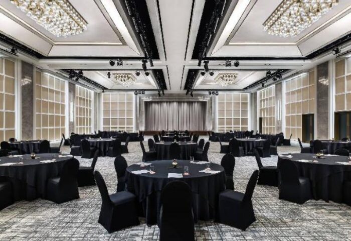 Le Meridien Seoul's elegant ballroom setup. Round tables with black linens and chairs. Chandeliers and stage area. Gay-friendly hotel.