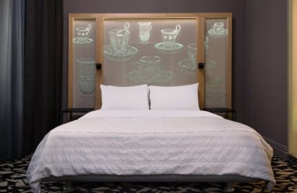 Le Meridien Vienna gay-friendly hotel: A bed with white linens and pillows. The headboard features a tea cup design. Modern, stylish room.