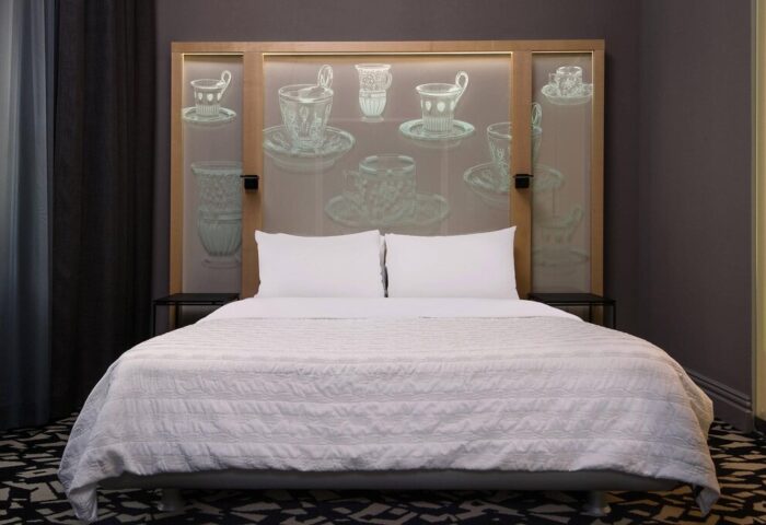 Le Meridien Vienna gay-friendly hotel: A bed with white linens and pillows. The headboard features a tea cup design. Modern, stylish room.