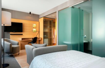 Le Méridien Vienna gay-friendly hotel room. Modern design with desk, TV, closet, and frosted glass bathroom. Upscale gay travel lodging.