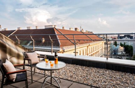 Le Meridien Vienna gay-friendly hotel terrace view. Drinks on table, chairs, city skyline. Perfect for gay travelers' Vienna stay.