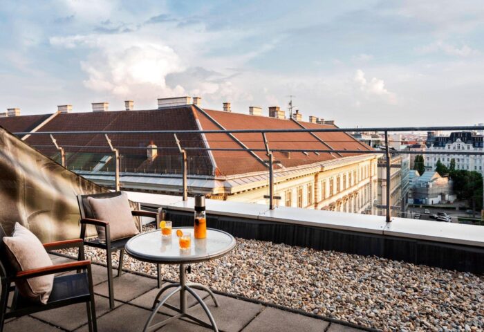 Le Meridien Vienna gay-friendly hotel terrace view. Drinks on table, chairs, city skyline. Perfect for gay travelers' Vienna stay.