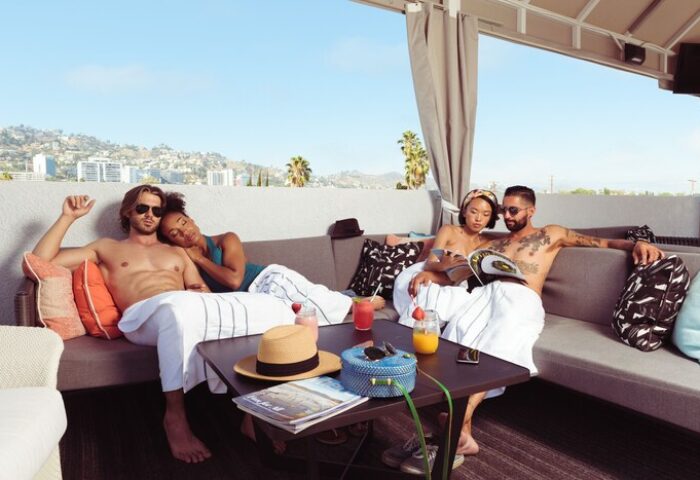 Le Parc at Melrose gay-friendly hotel rooftop. People relaxing on sofas, drinks on table, city view. Melrose hotel for gay travelers.