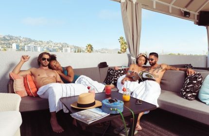 Le Parc at Melrose gay-friendly hotel rooftop. People relaxing on sofas, drinks on table, city view. Melrose hotel for gay travelers.