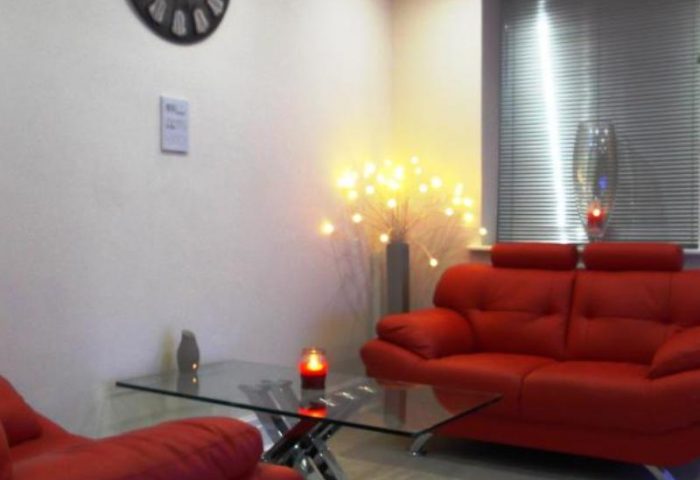 Le Ville Hotel's gay-friendly ambiance: Red sofa, glass table, and soft lighting create a welcoming space for gay travelers.