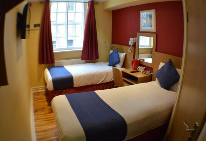 Le Ville Hotel gay-friendly room. Twin beds with blue accents, desk, and window. A comfortable stay for gay travelers.