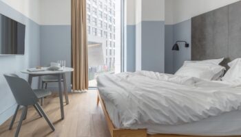 Leman Locke Hotel room interior. Modern, minimalist design with a bed, table, and large window. A gay-friendly hotel for the discerning traveler.