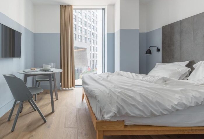Leman Locke Hotel room interior. Modern, minimalist design with a bed, table, and large window. A gay-friendly hotel for the discerning traveler.