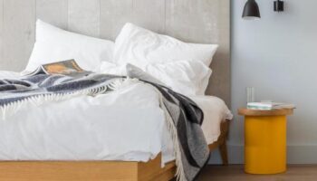Leman Locke hotel room with a bed, blanket, and yellow bedside table. Gay-friendly hotel design with modern interior. Perfect for gay travel.