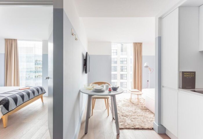 Leman Locke gay-friendly hotel room interior. Modern design, light wood floors, round table, and view into bedroom. London travel advice.