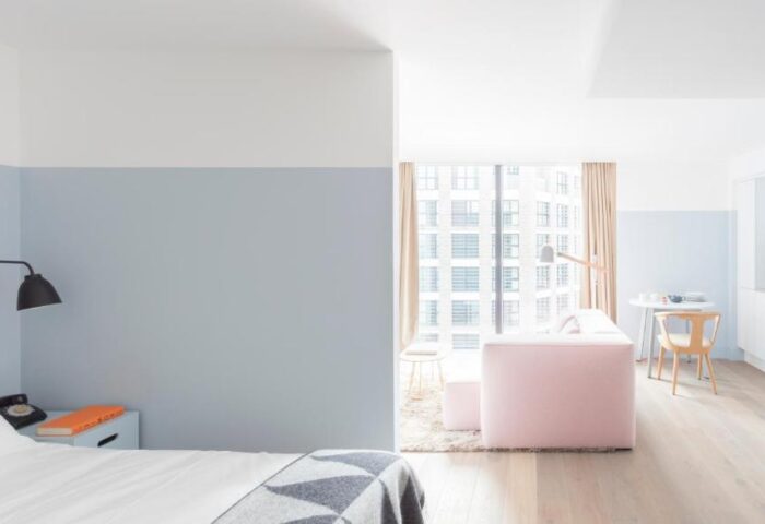 Leman Locke hotel room interior. Modern design with pink sofa, light wood floors, and a view of the city. Gay-friendly travel advice.