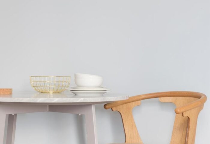 Leman Locke gay-friendly hotel detail: Table setting with plates, bowls, and a gold wire basket. Wooden chair. Minimalist design. Gay travel.