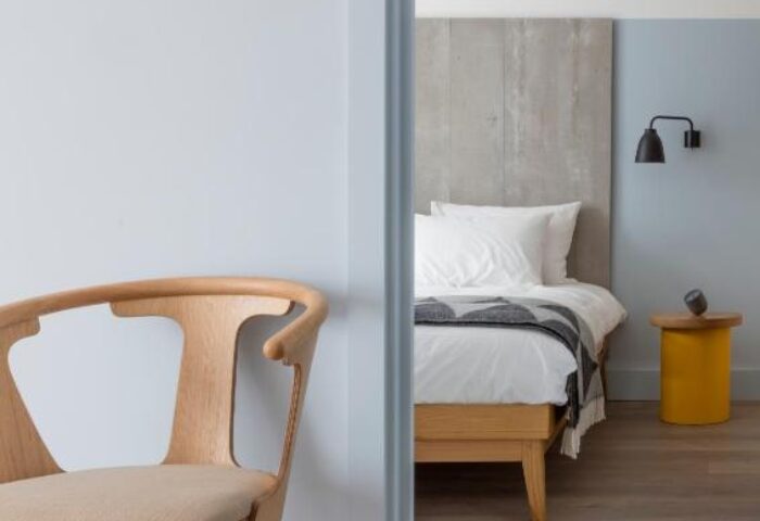 Leman Locke gay-friendly hotel room. Modern chair, bed, and yellow side table. Minimalist design in a London hotel. Travel advice for gay men.