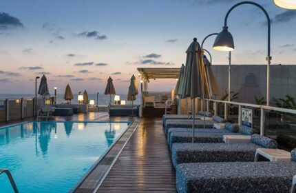 Leonardo Art Tel Aviv By the Beach: Poolside view at dusk. Gay-friendly hotel with lounge chairs, umbrellas, & ocean views. Perfect for gay travel.