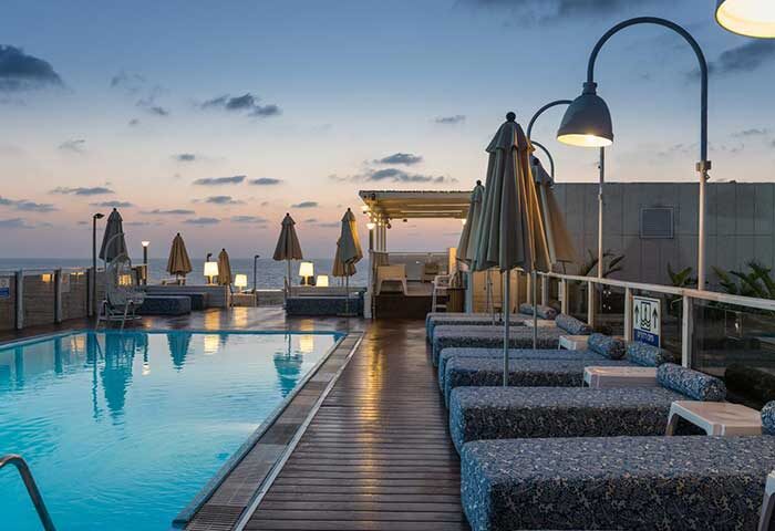 Leonardo Art Tel Aviv By the Beach: Poolside view at dusk. Gay-friendly hotel with lounge chairs, umbrellas, & ocean views. Perfect for gay travel.