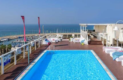 Rooftop pool at Leonardo Art Tel Aviv By the Beach, a gay-friendly hotel. Ocean view, lounge chairs, and modern design for gay travelers.