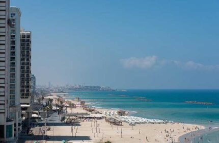 Tel Aviv beach view from Leonardo Art Hotel, a gay-friendly hotel by the beach. Sandy shore, blue sea, and city skyline.